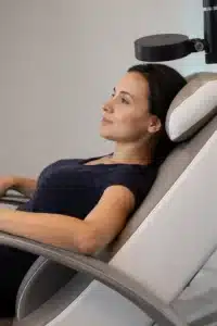 Patient reclining in the treatment chair during a neo TMS® session, the rTMS coil positioned above her head